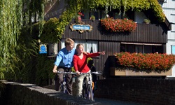 Zwei Radfahrer fahren stehen auf einer Brücke in Ulm, die Frau zeigt mit ihrer Hand auf etwas