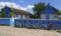 Ein paar Räder stehen an einem blauen Bretterzaun am Fischerdorf Lété im Donaudelta