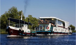 Das Floßhotel wird von einem Schiff über die Donau gezogen