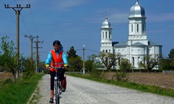 Ein Fahrradfahrer fährt auf einem Schotterweg am kleinen Kloster Saon im Donaudelta in Rumänien vorbei