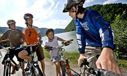 Eine Familie mit zwei Kindern machen eine kurze Stehpause auf dem Rad an der Donau