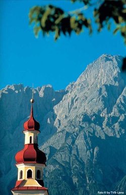 Blick auf eine Kirchturmspitze zu den Lienzer Dolomiten