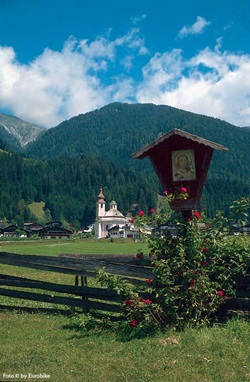 Blick über die Tiroler Landschaft an der Drau mit einer kleinen Holztafel am Wegesrand