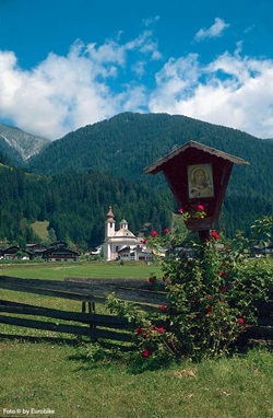 Blick über die Tiroler Landschaft an der Drau mit einer kleinen Holztafel am Wegesrand