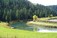 Der grünlich schimmernde Flusslauf des Inn schlängelt sich an saftigen Wiesen und dunkelgrünen Wäldern vorbei.