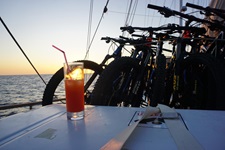 Ein orangener Cocktail steht auf einem Tisch des Deluxeschiffs Admiral, dahinter stehen die gesicherten Moutainbikes