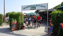 Drei Fahrradfahrer stehen unter eineim Biergartenschild auf der Radreise von Wien nach Budapest neben ihren Rädern
