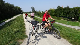 Radfahrer auf dem schottrigen Donau-Radweg, auf dem ein abgestelltes Fahrrad steht