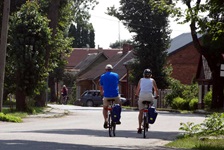 Zwei Radfahrer radeln durch ein masurisches Dorf.