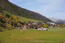 Blick auf den von saftigen Wiesen, dunkelgrünen Nadelwäldern und hoch aufragenden Bergen umgebenen Ort Muenster.