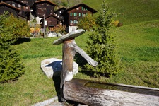 Fantasievoll gestalteter Brunnen vor den Holzchalets von Niederwald.