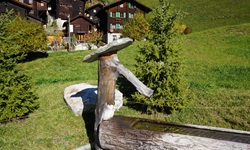 Fantasievoll gestalteter Brunnen vor den Holzchalets von Niederwald.