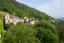 Die Häuser eines ligurischen Dorfes schmiegen sich idyllisch zwischen die sie umgebenden Bäume.