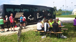 Die Radlergruppe der Gruppenreise Venetien beim Picknick mit Biertischgarnituren vor dem schwarzen Reisebus