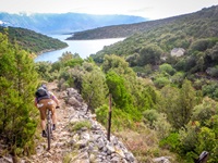 Ein Mountainbiker fährt auf der Insel Brac über einen steinigen Naturweg hinunter zum Meer.