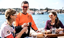 Ein Mann und zwei Frauen gönnen sich in einem süddalmatinischen Hafen eine Kaffeepause.