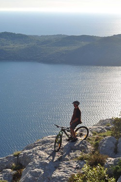 Ein Mountainbiker schaut von den Klippen der Insel Hvar hinab auf's Meer.