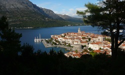 Blick von einem Aussichtspunkt auf die beeindruckende Hafenstadt Korcula in Kroatien mit angelegten Booten und Schiffen