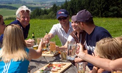 Eine Gruppe genießt ihr Vesper und prostet sich mit verschiedenen Getränken zu