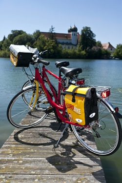 Zwei Räder stehen auf einem Holzsteg im Klostersee und im Hintergrund ist das ehemalige Kloster Seeon zu sehen