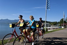 Radler am Chiemsee fahren an einer Bootsanlegestelle vorbei