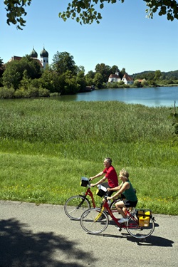 Zwei Radfahrer radeln in Seebruck am Klostersee vorbei