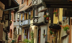 Ein Mann steht in einer Gasse von typischen Fachwerkhäusern in Eguisheim im Elsass