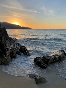 Romantischer Sonnenuntergang über einem Sandstrand an der Küste der Insel Elba.