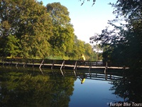 Ein Radler überquert eine Holzbrücke über einen Fluss auf der Drei-Länder Weintour