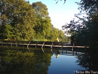 Ein Radler überquert eine Holzbrücke über einen Fluss auf der Drei-Länder Weintour