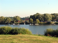 Blick vom Elbufer zur anderen Flussseite, an der einige Boote vertäut liegen.