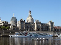 Ein Passagierschiff und ein Ruderboot passieren das Dresdner Elbufer mit dem Lipsius-Bau, der heute die Hochschule für Bildende Künste beherbergt, und der Frauenkirche.