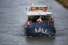 Das Schiff L´Estello von vorne mit zwei Passagieren, von dem einer auf dem Bug Gitarre spielt