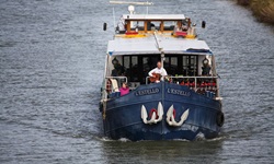 Das Schiff L´Estello von vorne mit zwei Passagieren, von dem einer auf dem Bug Gitarre spielt