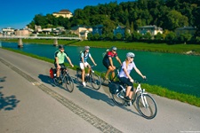 Vier Radler fahren auf einem asphaltierten Radweg an der Salzach entlang.