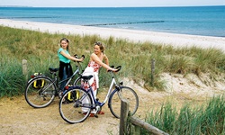 Zwei Radlerinnen schieben ihre Räder an den Strand der Ostsee