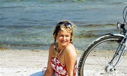Blick auf eine Radlerin, die am Strand neben ihrem Rad sitzt