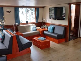 Blick in die moderne Lounge mit lederbezogenen Bänken und TV-Gerät auf der MS La Mar (ehemals Fiep)