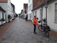Eine Radlerin steht in einer Fischereidorf in Schleswig