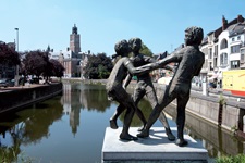 Statue mit tanzenden Kindern in Dendermonde; im Hintergrund der markante, rot-weiß gestreifte Gerichtshof.