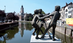 Statue mit tanzenden Kindern in Dendermonde; im Hintergrund der markante, rot-weiß gestreifte Gerichtshof.