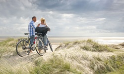 Zwei Radfahrer stehen auf einer Düne auf der Insel Föhr und blick auf das Meer