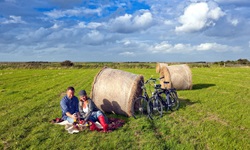 Zwei Fahrradfahrer machen an einem Strohballen auf einem Feld ein Picknick auf der Insel Föhr