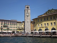 Blick auf einen Hafen am Gardasee mit Promenade und einem Turm mit Uhr