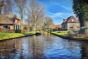 Blick über einen Kanal zu einer Kanalbrücke und den umliegenden Häusern in Giethoorn