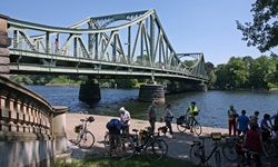 Eine Radlergruppe macht unterhalb der Glienicker Brücke, dem Bindeglied zwischen Berlin und Potsdam, eine Pause.