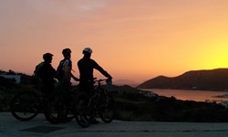 Drei Mountainbiker genießen einen herrlichen Sonnenuntergang über Lipsi.