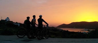 Drei Mountainbiker genießen einen herrlichen Sonnenuntergang über Lipsi.