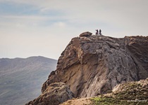 Zwei Mountainbiker stehen auf einem Felsblock und genießen die Aussicht.