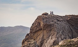 Zwei Mountainbiker stehen auf einem Felsblock und genießen die Aussicht.